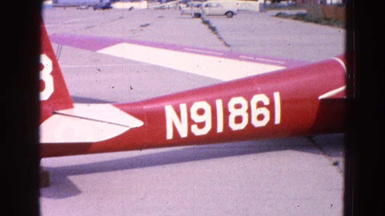 1964 Washington, DC frame showing the red fuselage of the aircraft with white registration N91861 and partial tail markings on the tarmac.