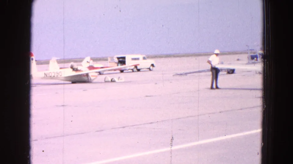 1964 Washington-area airfield footage showing small white aircraft on the tarmac, a man standing in a cap, and a white van nearby.