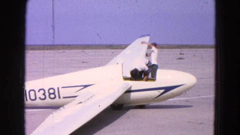 A side view shows the 1964 glider inspection continuing, with one man bent near the cockpit and another standing beside the fuselage.