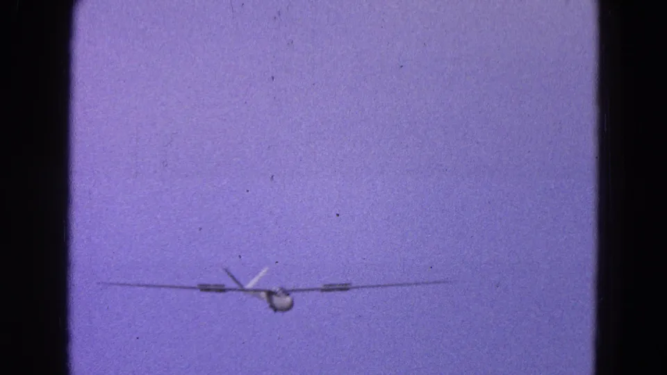 Distant light aircraft in a 1964 Washington, DC 8mm frame, with purple color cast and visible film gate edges.