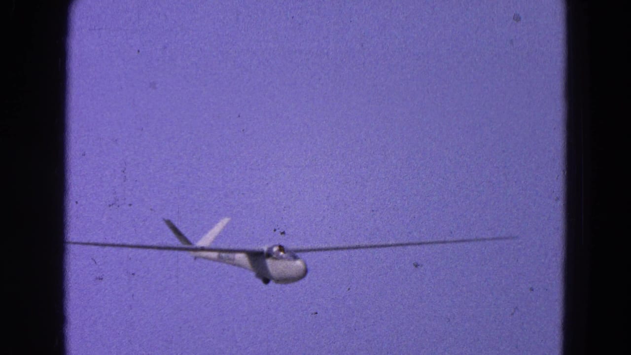 The glider appears larger in frame as it descends, with 8mm grain and dark film borders visible.