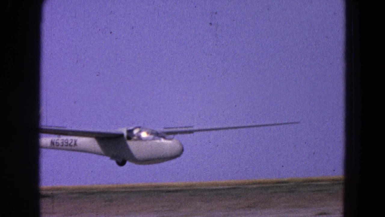 White glider beginning takeoff beside a runway under a blue-purple sky.