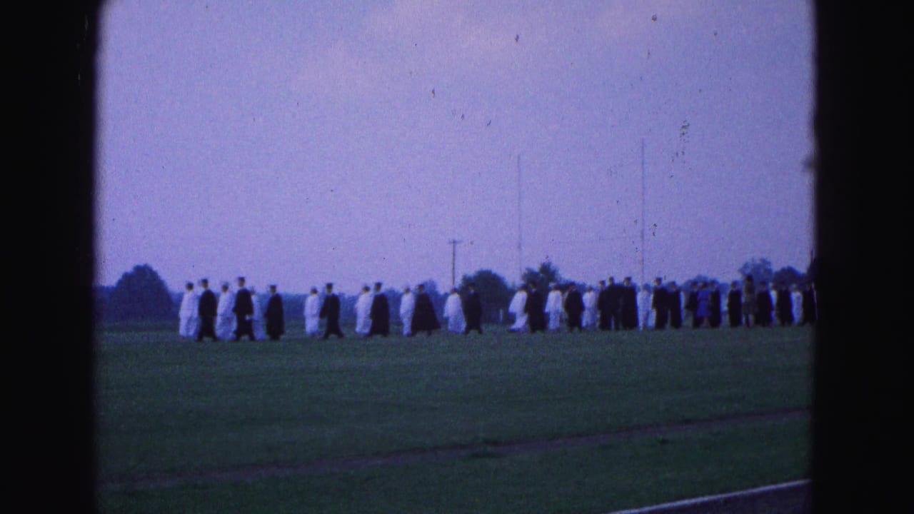 A long line of robed students continues across the field.