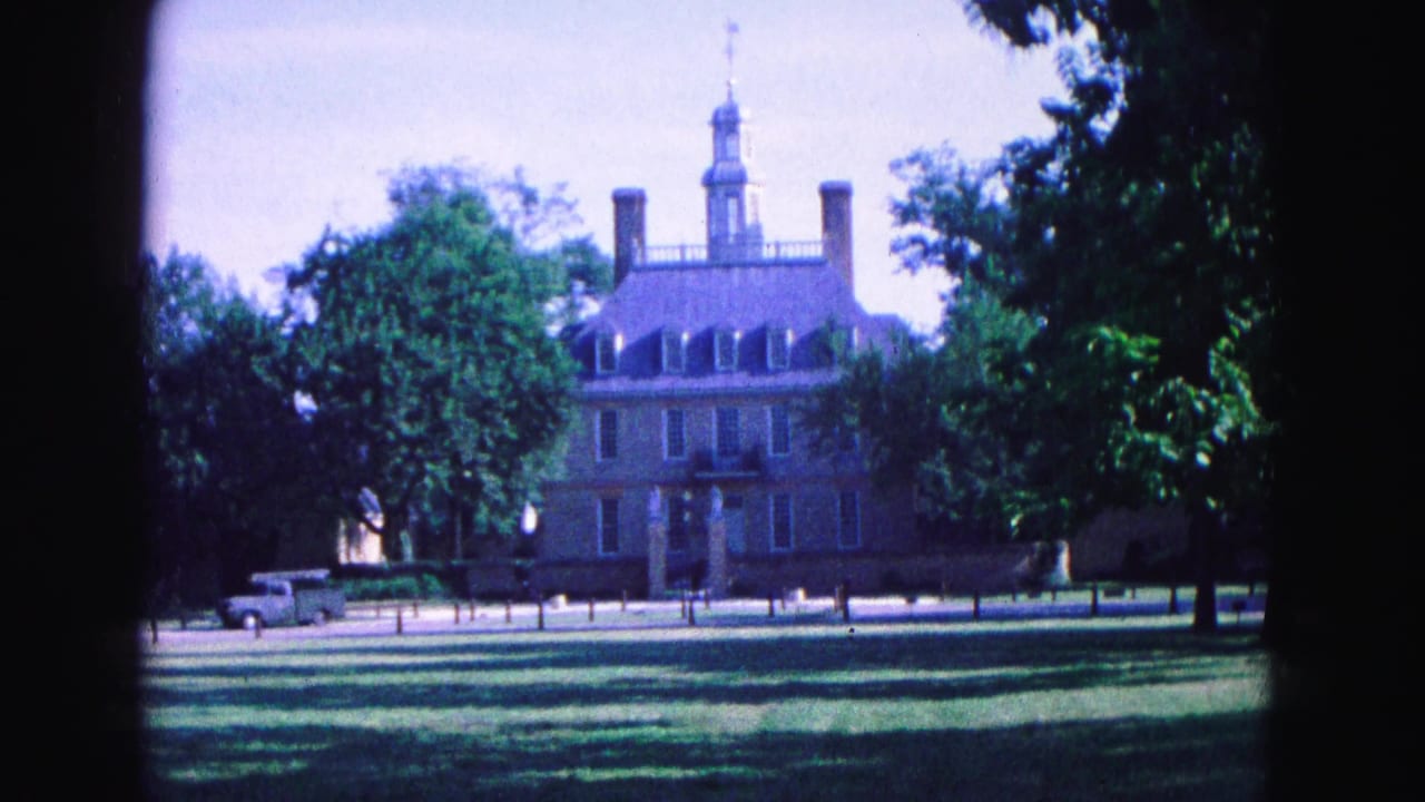 Historic brick building with cupola, trees, lawn, and a light-colored pickup parked nearby.