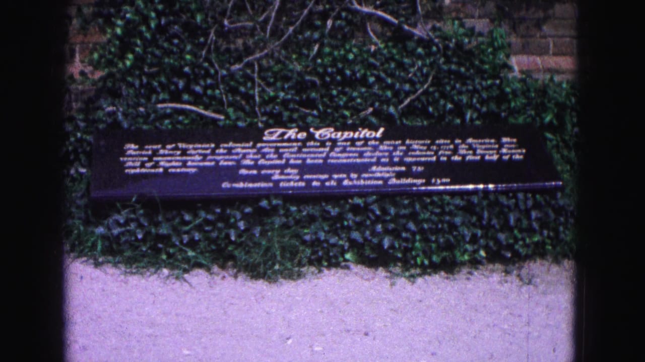 Dark Capitol sign stands in front of ivy and a brick wall.
