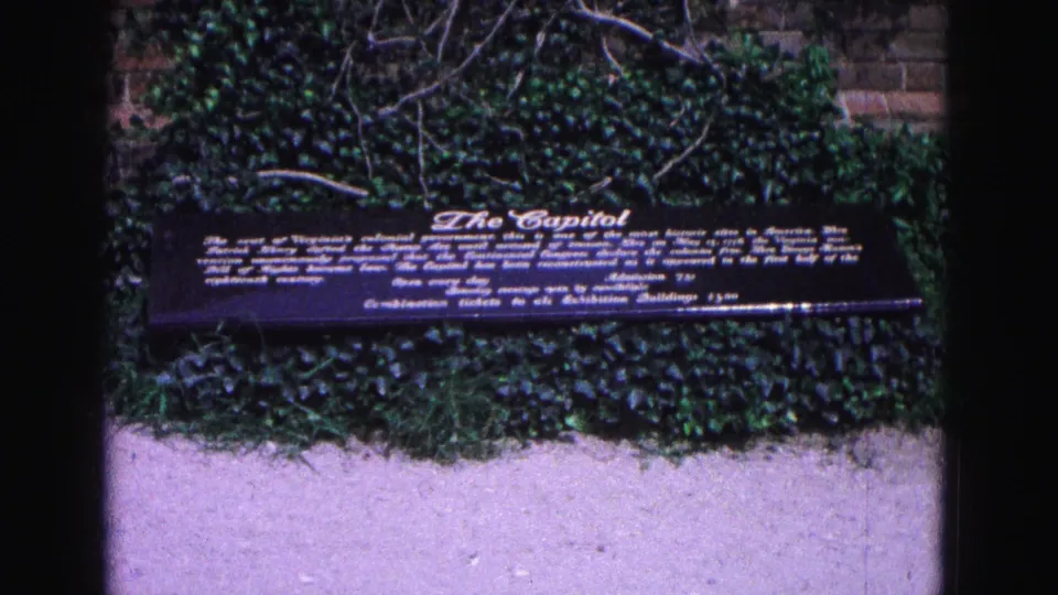A readable Capitol interpretive sign appears against ivy and brickwork at the Williamsburg historic site.