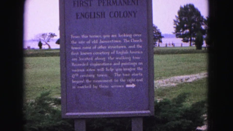1964 Williamsburg-area 8mm frame showing a First Permanent English Colony marker near open grass, trees, and water.