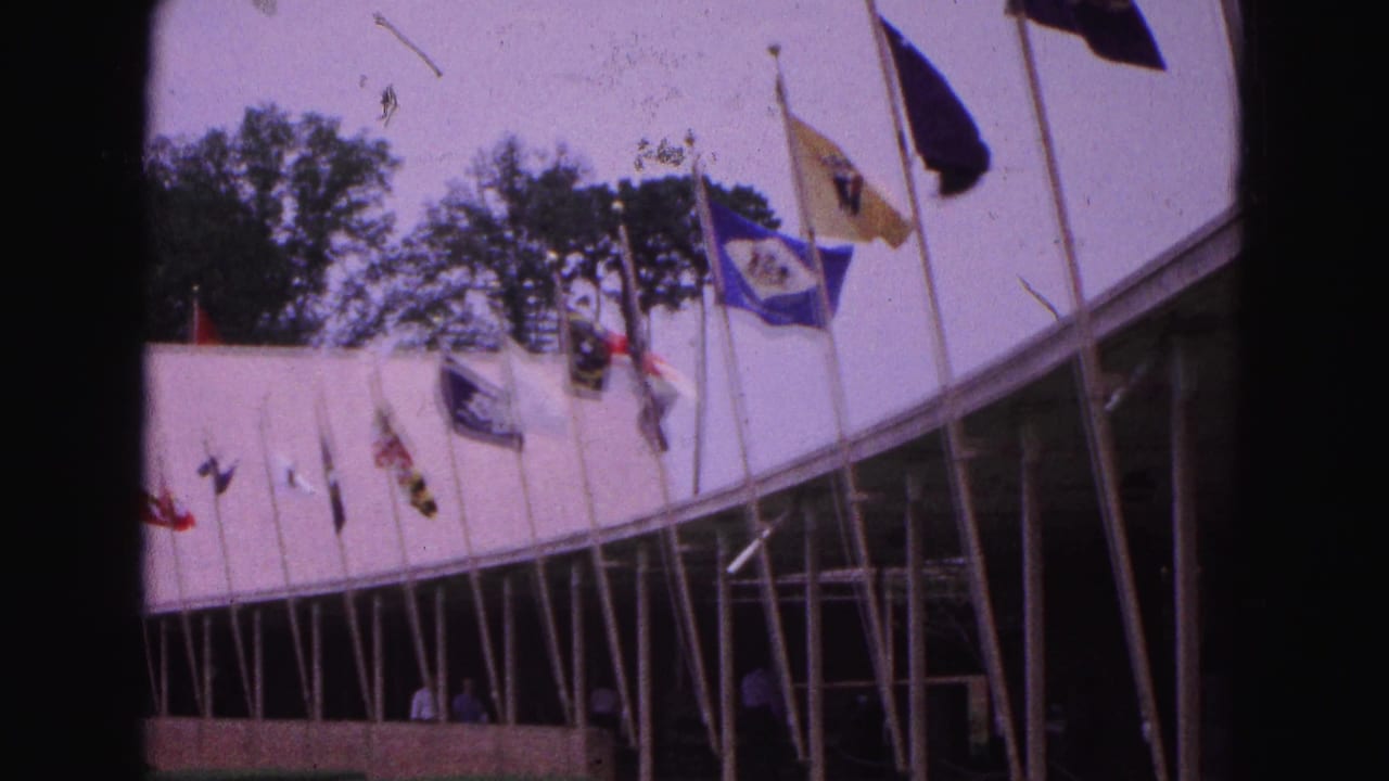 Curved pavilion with rows of flags above a shaded walkway.