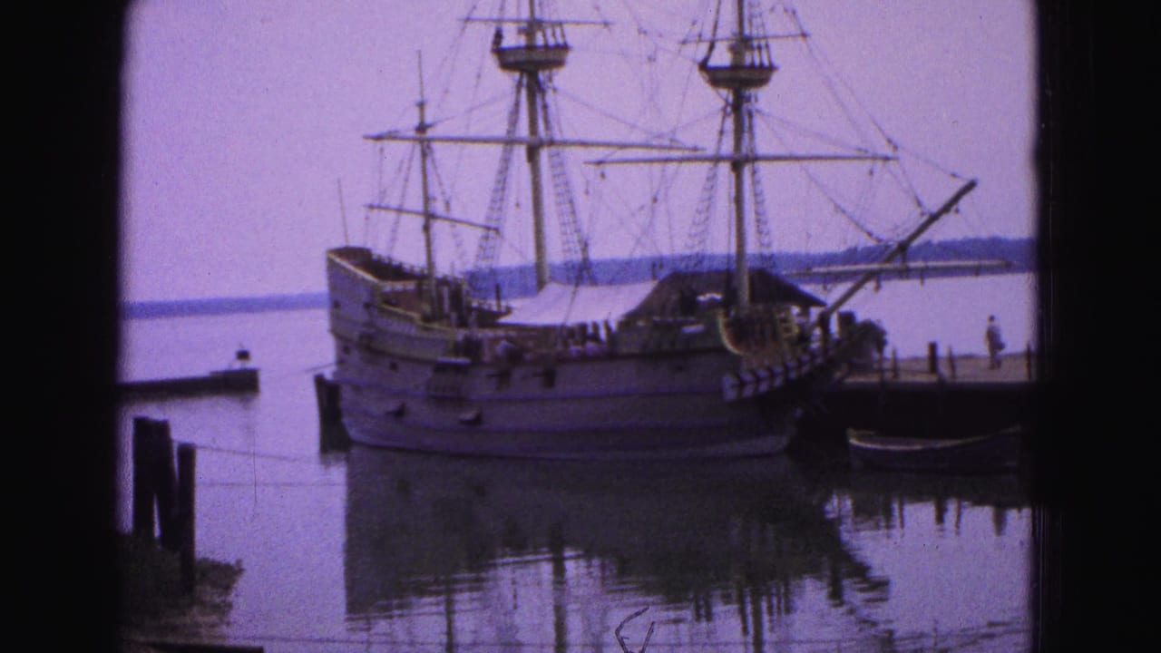 The Susan Constant replica appears docked in Williamsburg, Virginia, with rigging visible above a quiet pier and reflected harbor water.