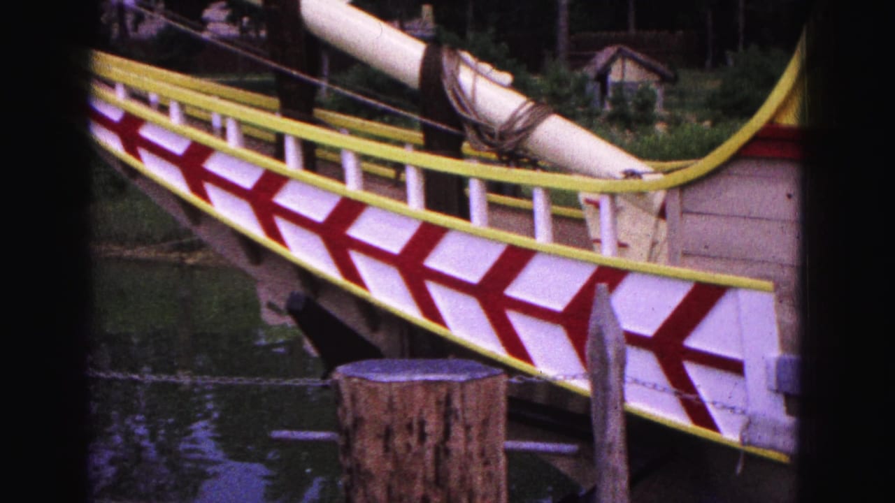 Williamsburg 1964 home-movie view of a painted replica ship hull with yellow rails, red and white chevrons and water below.