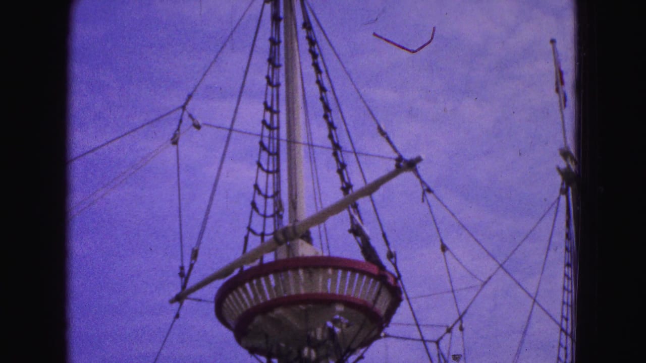 Ship mast, crow's nest, ropes, and rigging against a blue-purple sky.