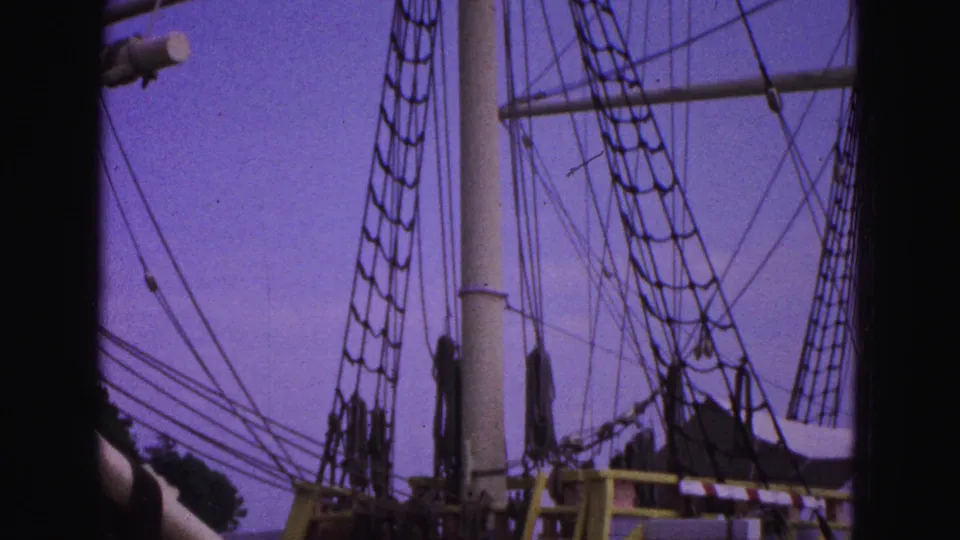 The camera angle drops toward the sailing ship's lower rigging and deck area, with painted structures visible below.