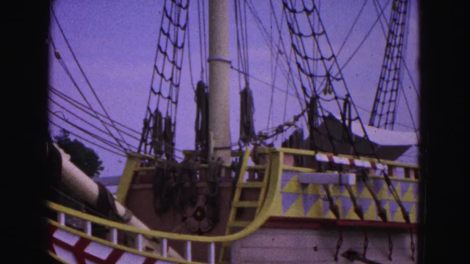 1964 8mm frame showing the historic ship's deck area with a yellow rail, patterned paintwork, mast base and rigging.