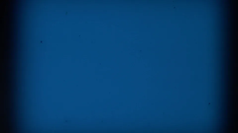 Blue leader-like 8mm frame from the 1965 Clarkson, Nebraska clip, with dark borders, grain, and small specks.