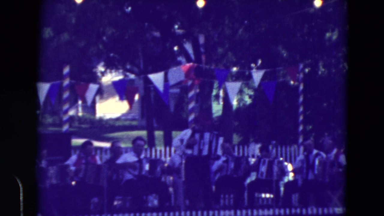 1965 Clarkson, Nebraska home-movie frame showing accordion musicians and spectators at an outdoor community festival.