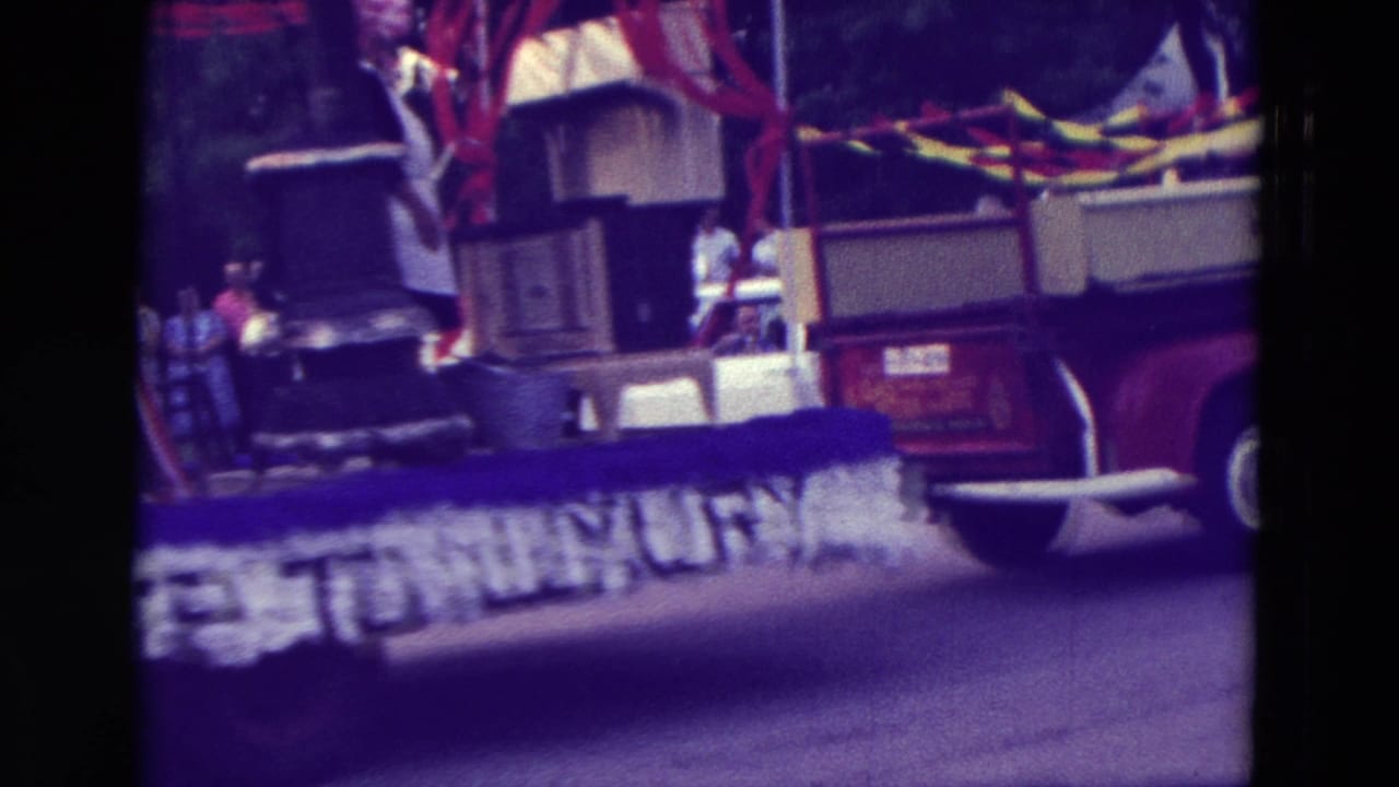 1965 Clarkson, Nebraska parade float with household appliances, red streamers, and a partly obscured Hardship to Luxury banner.