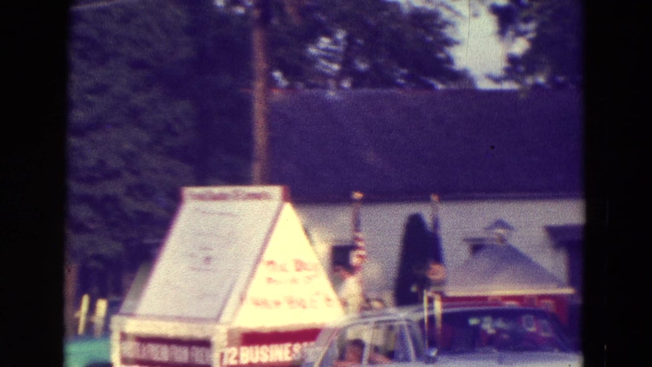 Triangular festival display beside parked cars and a building roofline.