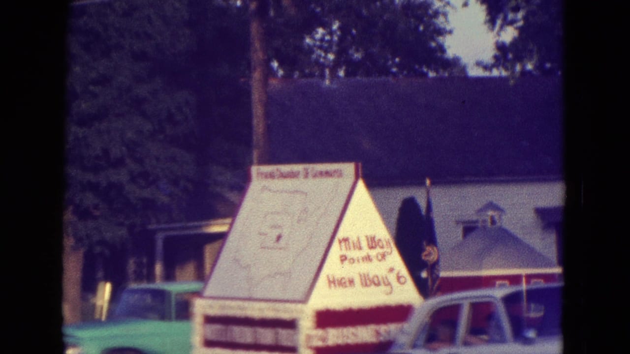 Highway 6 themed triangular display with cars and flags nearby.