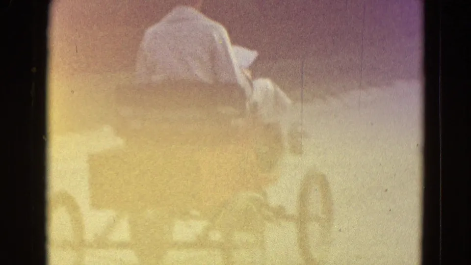 The 8mm frame blooms with exposure as the rider and red go-kart appear faintly against the street and grass.