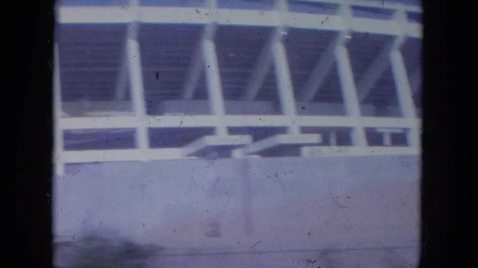Closer 1965 Louisville view of white stadium supports and seating structure above a concrete wall.