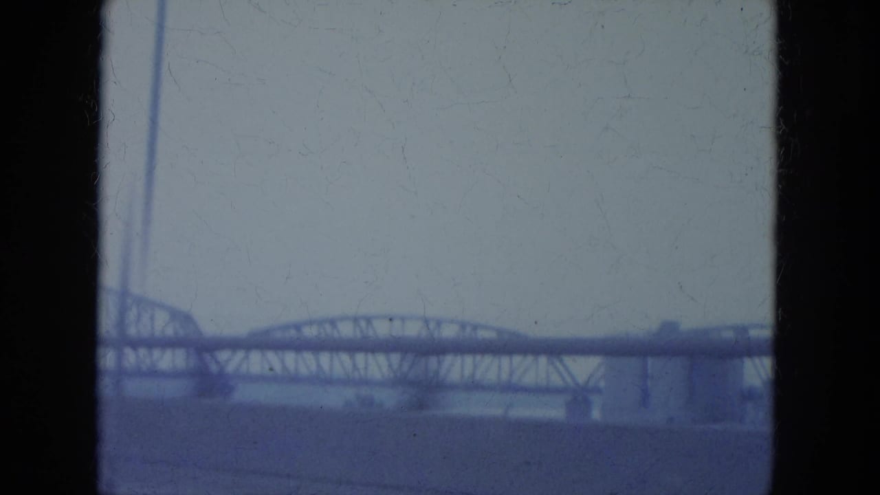 Distant steel truss bridge seen through an 8mm film frame.
