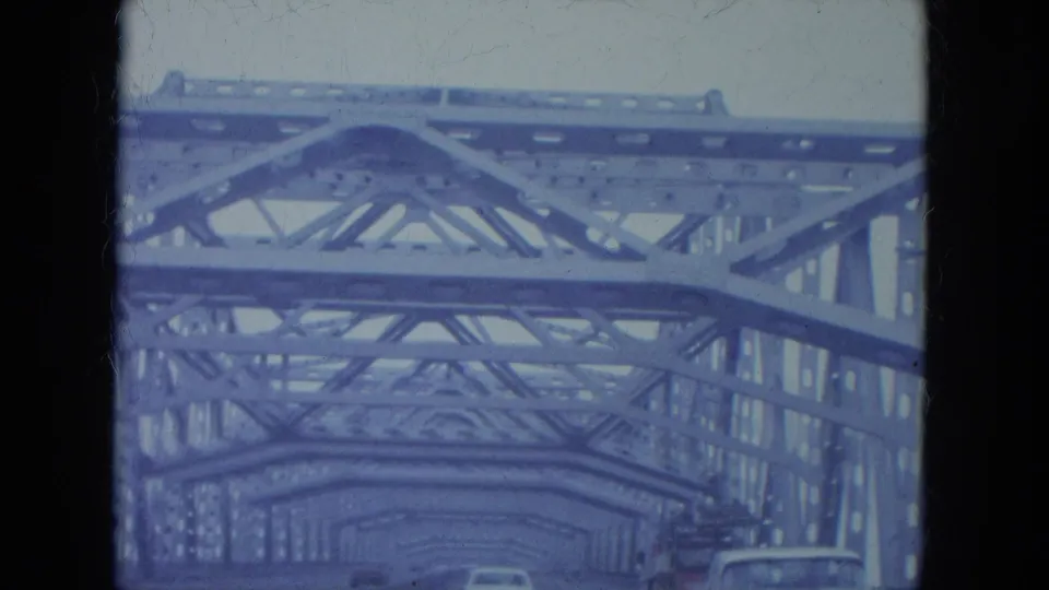 1965 Louisville driving view beneath a steel truss bridge, with cars moving through the metal framework.