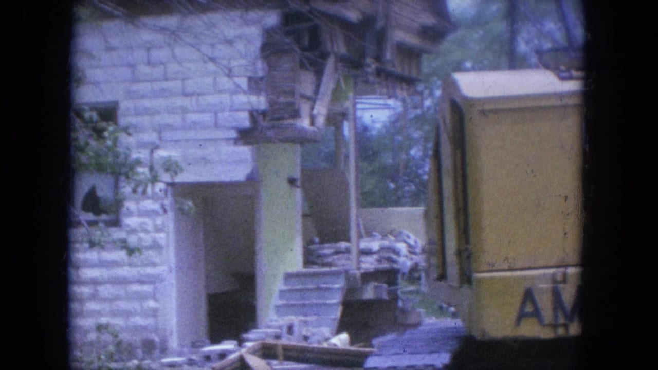 Partial view of excavator and damaged house seen through 8mm frame borders.