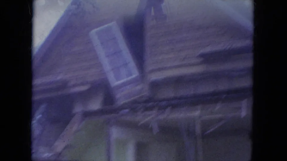 1965 Louisville 8mm frame showing a tilted close view of a damaged house exterior with a window and exposed framing.