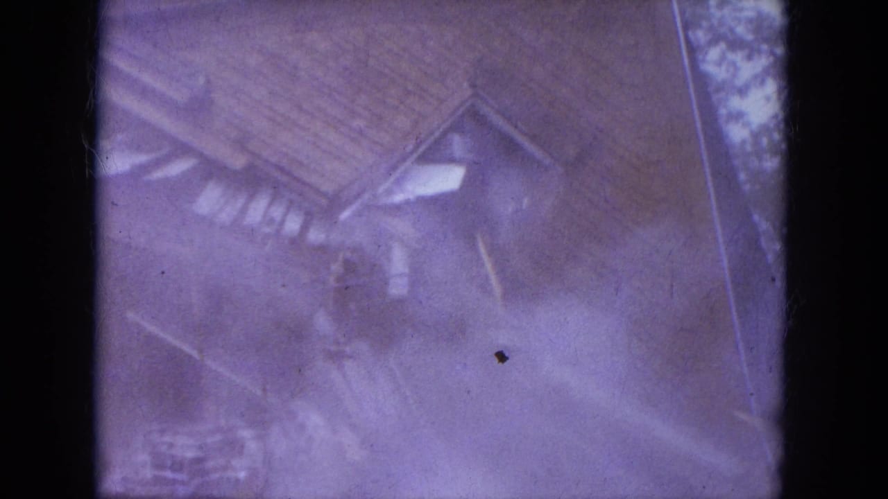 Soft purple frame of a small house roof and wall partly obscured by film blur and border.
