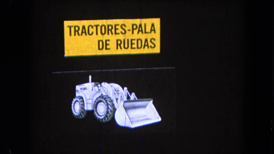 1965 Pueblo, Mexico 8mm frame showing Spanish text reading “TRACTORES-PALA DE RUEDAS” above a white wheeled loader illustration.