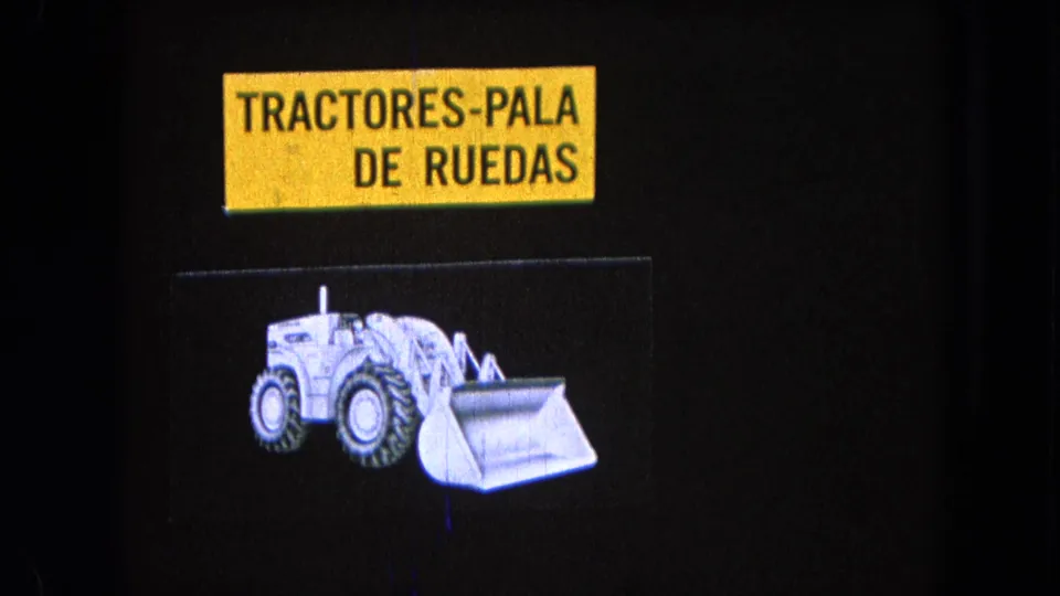 A grainy 8mm view of the Spanish “TRACTORES-PALA DE RUEDAS” card and wheeled loader graphic, supported by the 1965 Pueblo, Mexico metadata.