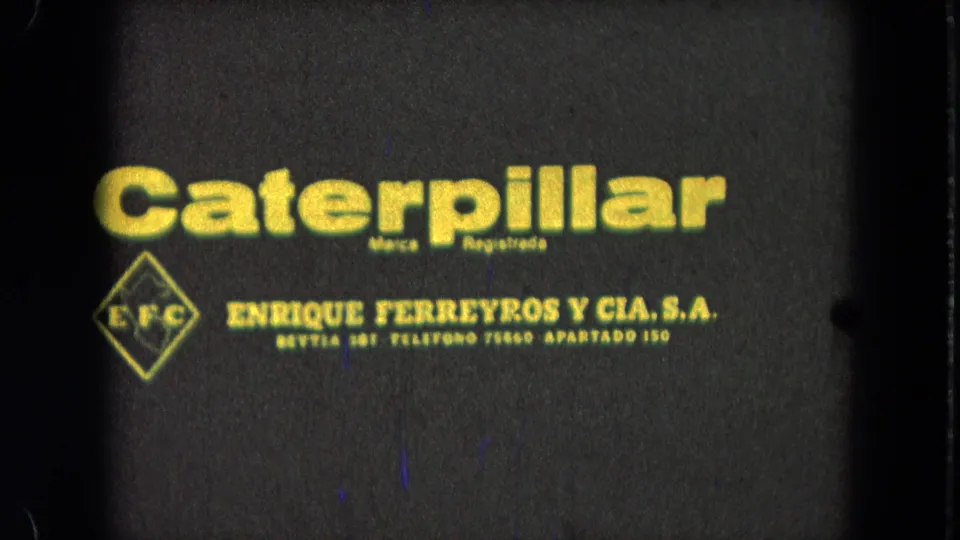 1965 Pueblo, Mexico 8mm frame showing yellow Caterpillar and Enrique Ferreyros y Cia. S.A. lettering with visible film wear.