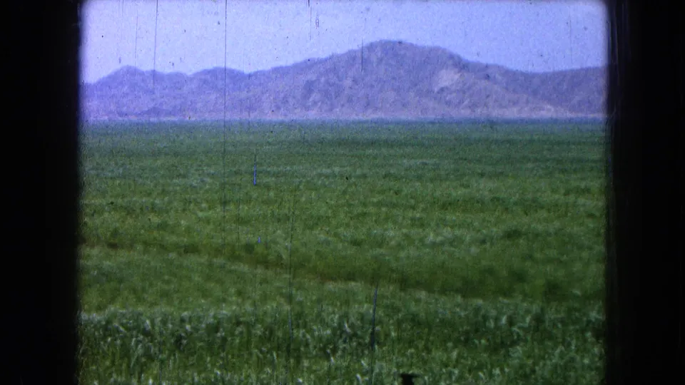 Final 1965 8mm landscape frame showing green open land and a distant mountain ridge in the recorded Pueblo, Mexico setting.