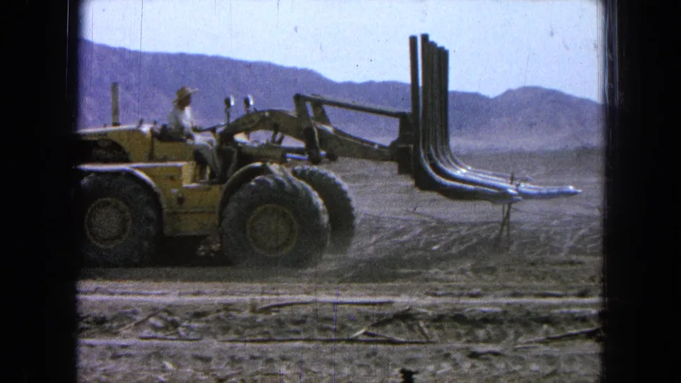 In the final frame, the loader is seen in profile with the operator seated and the grapple attachment held forward.