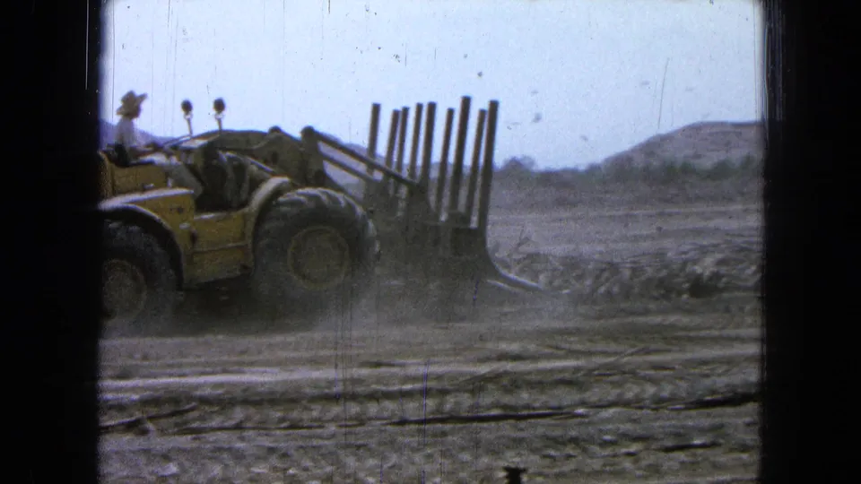 The loader and fork attachment pass close to the camera in dusty 8mm footage from Pueblo, Mexico, 1965.