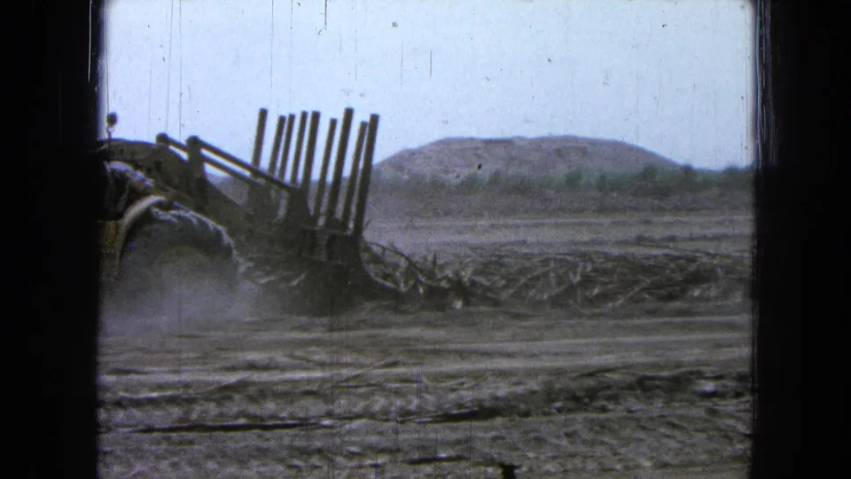 The final frame shows the loader leaving the shot, with fork tines, dust, dry ground, and low hills visible in 1965 Mexico footage.