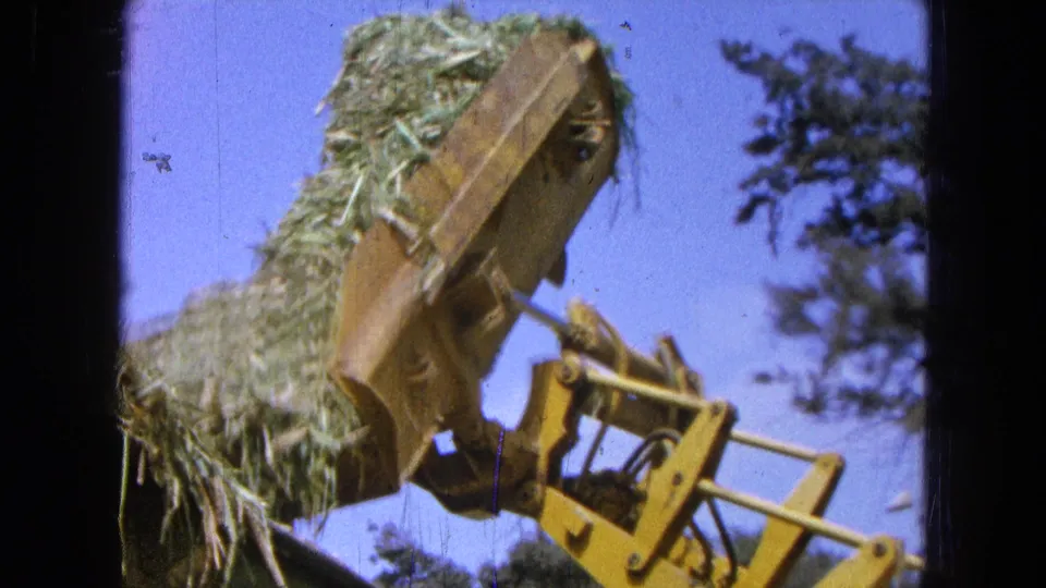 The final frame shows the side of the yellow hay loader and its metal linkages in the Pueblo, Mexico 1965 farm scene.