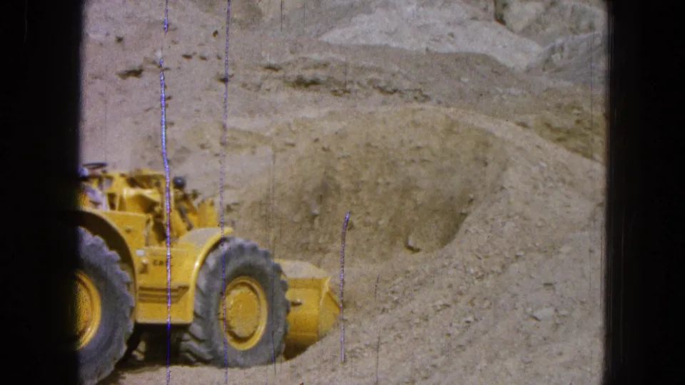 1965 Pueblo, Mexico 8mm frame with the loader cropped close as it works beside loose dirt and gravel.