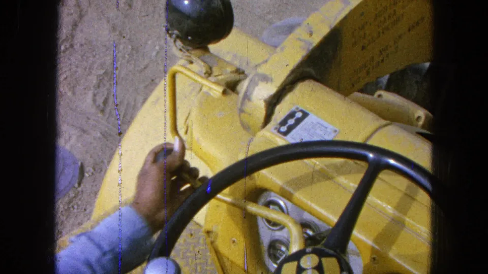 The final frame shows a yellow vehicle dashboard with a steering wheel, gauges, levers, and an operator's hand.