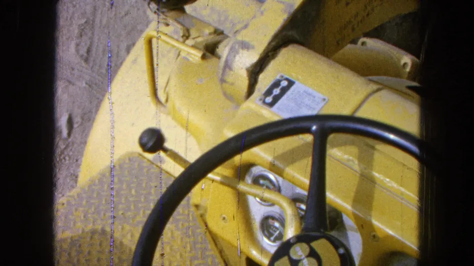 Close 8mm view of yellow heavy equipment controls in Pueblo, Mexico, with a steering wheel, gauges and label plate visible.