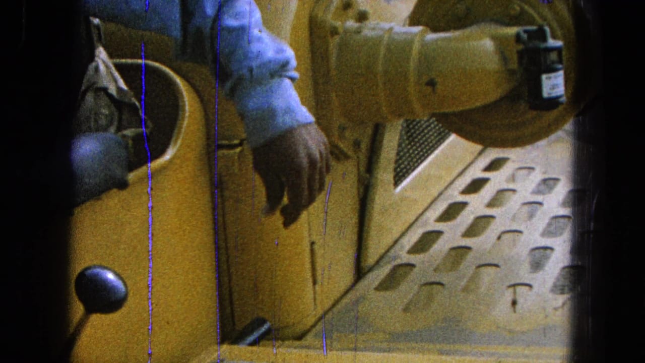 Close view of a yellow loader cab with an operator's arm and step plate visible.