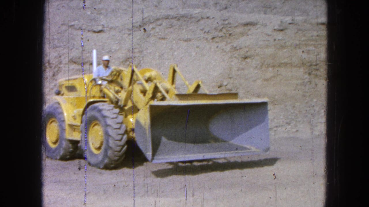 Front-end loader faces the camera with its bucket lowered near the ground.