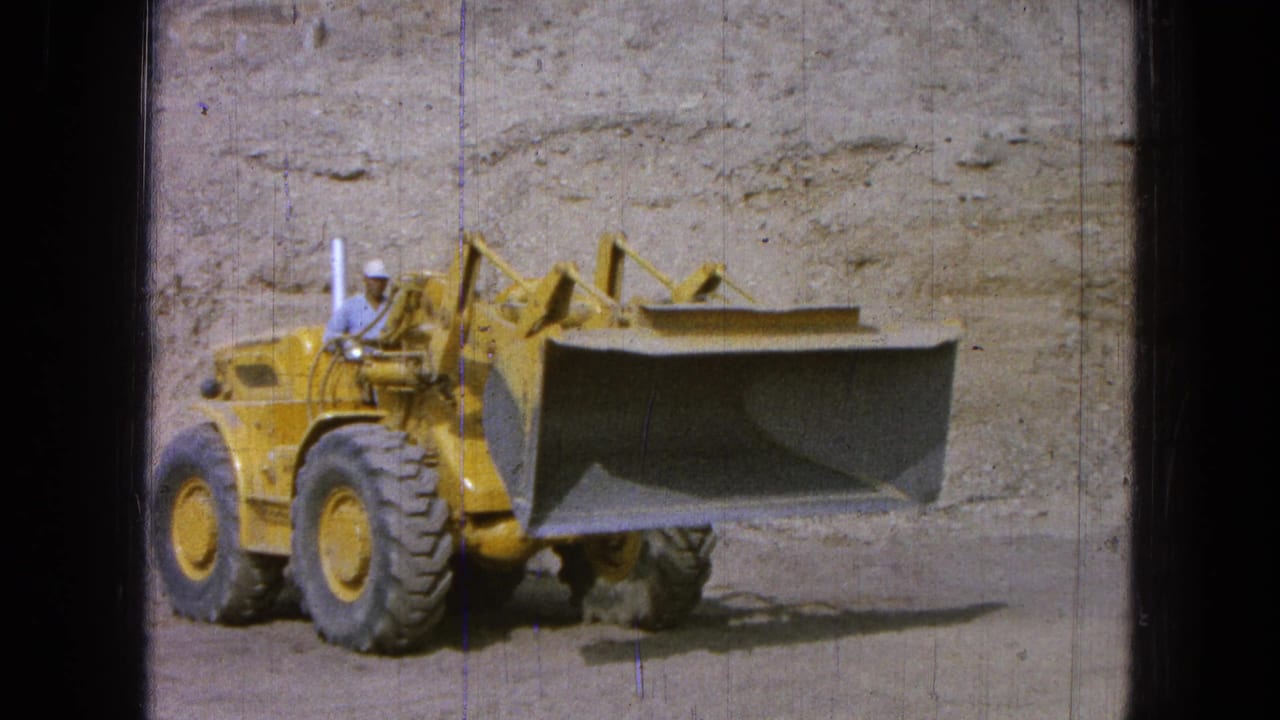 Front-end loader faces the camera with its large bucket raised at a worksite.