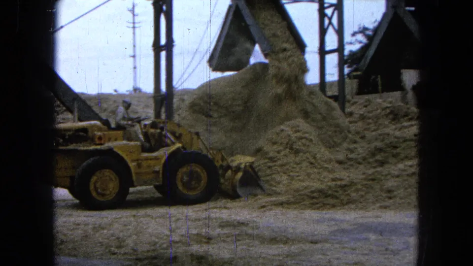 1965 Pueblo, Mexico 8mm frame showing a loader dumping loose material onto a large pile at an outdoor construction site.