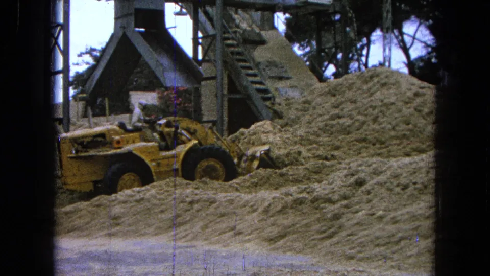 The final 1965 Pueblo, Mexico frame shows the loader and operator partly covered by the foreground mound near industrial structures.