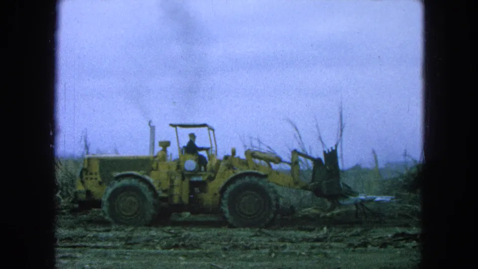 A side view shows the yellow front-end loader and bucket working near sugarcane in the Pueblo, Mexico 1965 home-movie footage.