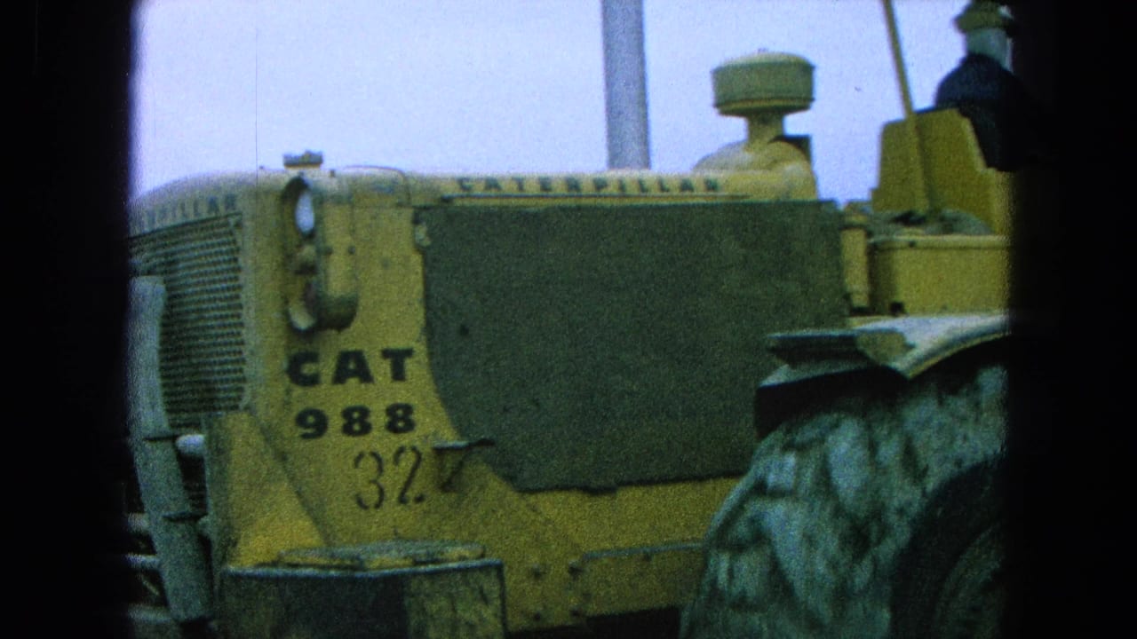 Yellow CAT 988 machine fills the frame with a driver partly visible above it.