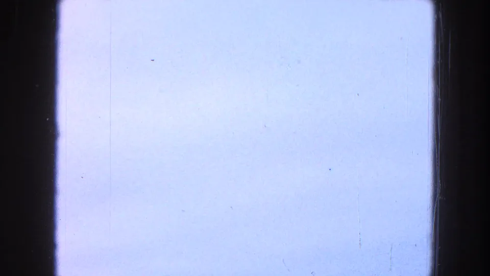 A mostly overexposed 8mm frame with pale sky, faint film scratches, and dark frame edges between clearer field shots.