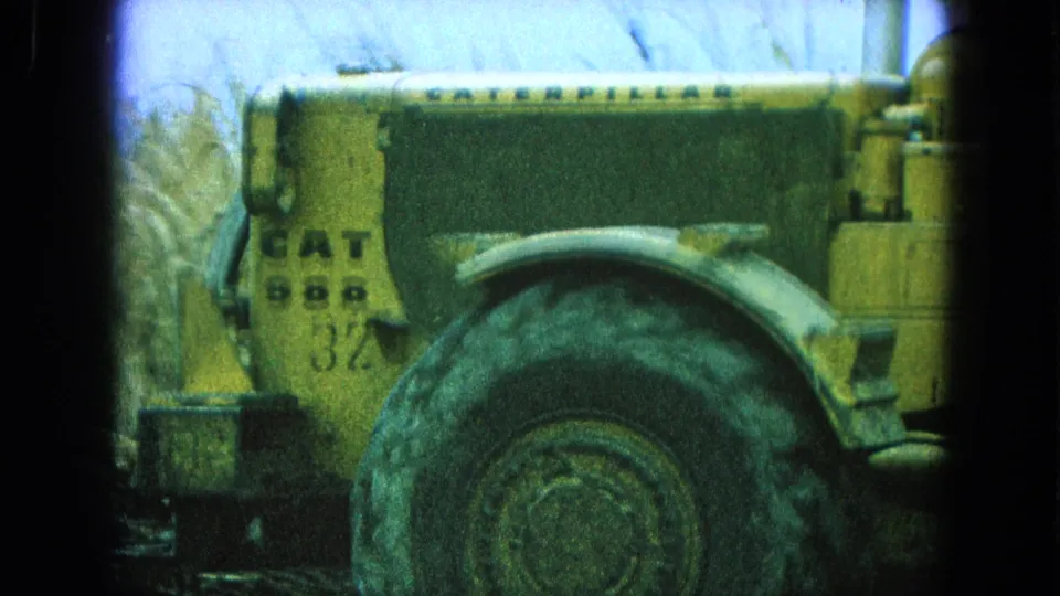1965 home-movie frame from Pueblo Mexico showing the CAT 988 marking and oversized tire on a yellow loader.