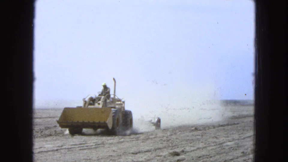The tractor moves closer through the dry field, with dust and field ridges visible in this 1965 Pueblo, Mexico home-movie frame.
